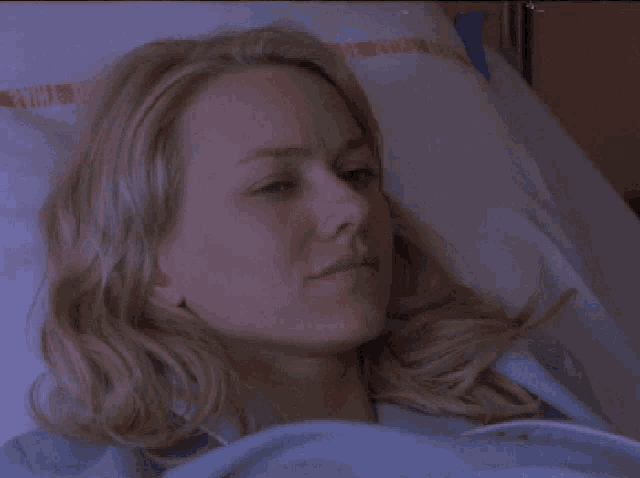 a woman is laying in a hospital bed with a blanket that says ' a ' on it