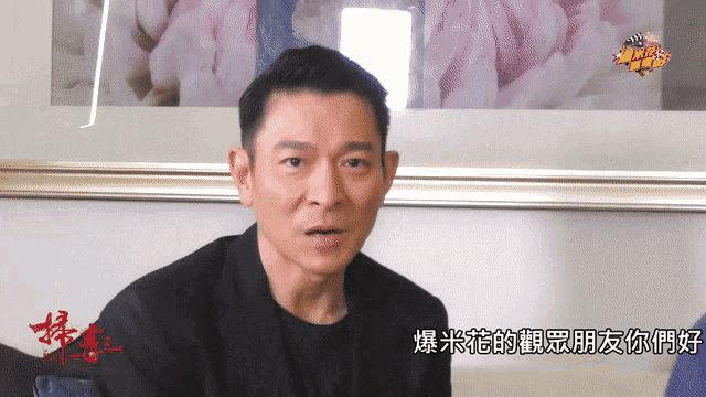 a man sitting in front of a framed picture with chinese characters on it