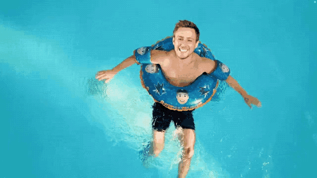 a man is floating in a swimming pool wearing a blue inner tube with sharks on it