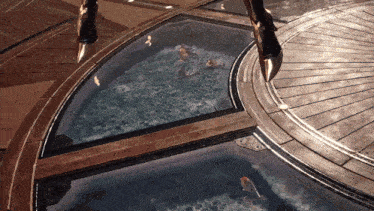 a person standing next to a pool of water with fish swimming in it
