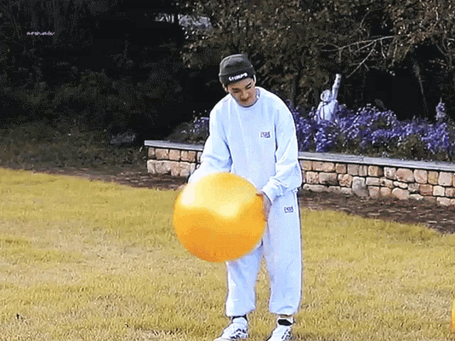 a man wearing a hat that says ' urban ' on it holds a large orange ball
