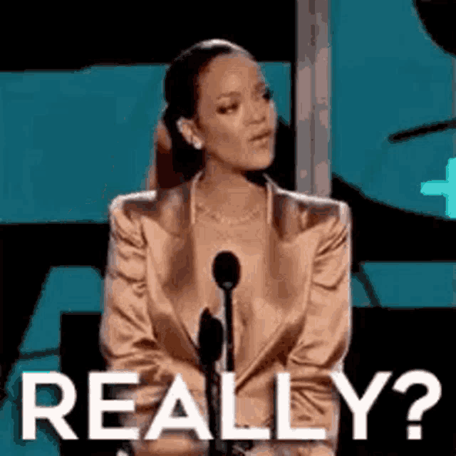 a woman in a suit is sitting in front of a microphone and asking , `` really ? ''