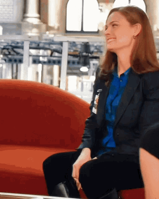 a woman in a blue shirt and black jacket has a name tag on her shoulder
