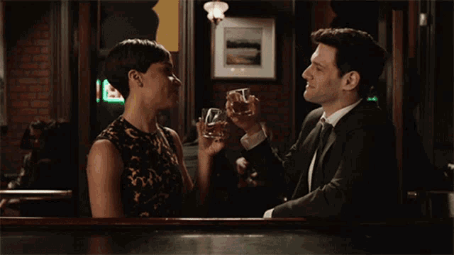 a man and a woman are drinking at a bar with a sign that says ' a ' on it