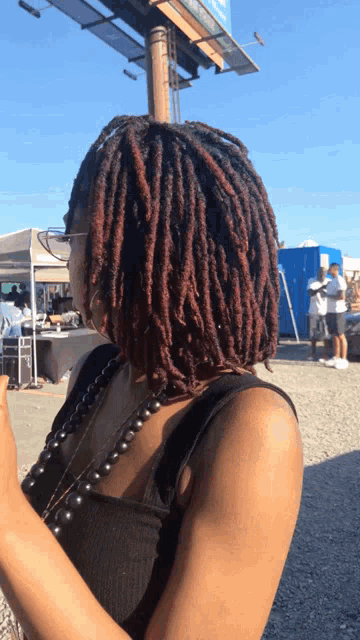a woman with dreadlocks and glasses is standing in front of a billboard