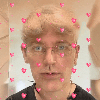 a man wearing glasses and a black shirt is surrounded by pink hearts