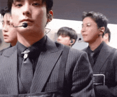a man in a suit and tie is wearing a microphone on his ear .