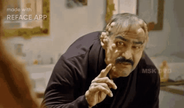 a man with a mustache is making a face with his finger