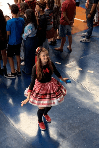 a girl in a red and black plaid skirt is dancing