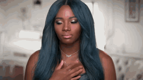 a woman with long blue hair is wearing a necklace and a wig .