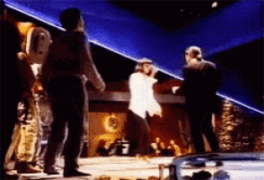 a man in a white shirt is dancing on a stage in front of a crowd
