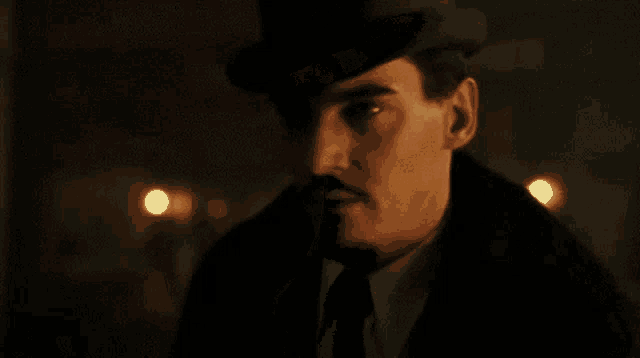 a man with a mustache is wearing a hat and a coat .