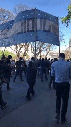 a group of people are walking down a street with a large blue flag that says " uruguay "