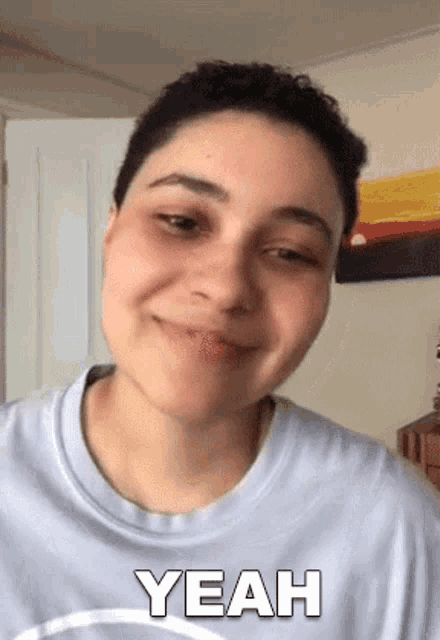 a woman in a blue shirt is smiling and says yeah