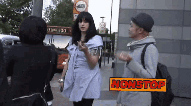 a man and a woman are standing on a sidewalk with a sign that says nonstop