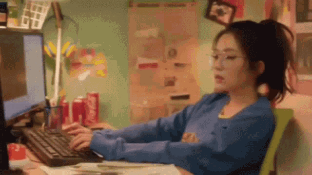 a woman is sitting at a desk with a computer and a keyboard .