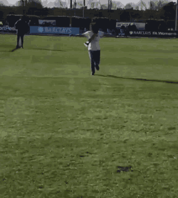 a woman kneeling on the grass with her arms outstretched in front of a banner for barclays
