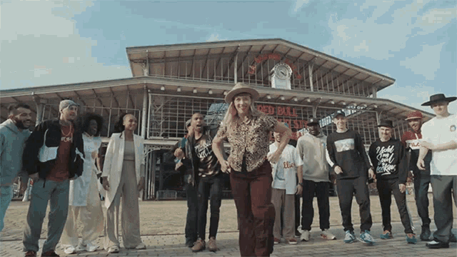 a group of people are dancing in front of a building that says red bull