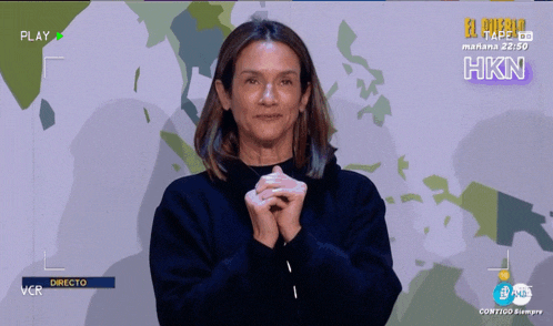 a woman with her hands folded in front of a screen that says play