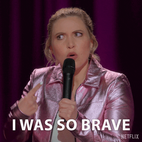 a woman holding a microphone and saying i was so brave