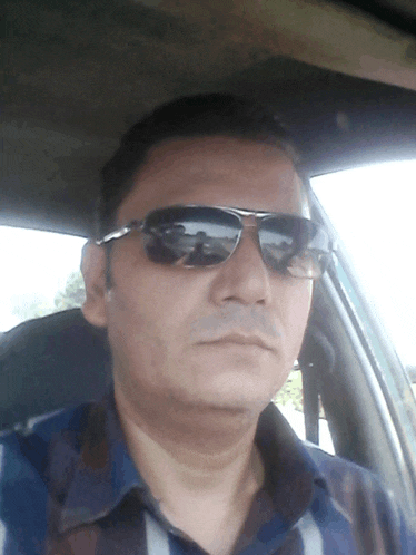 a man wearing sunglasses sits in a car