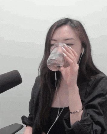 a woman is drinking from a plastic cup while wearing headphones