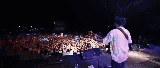 a man is playing a guitar in front of a crowd at a concert
