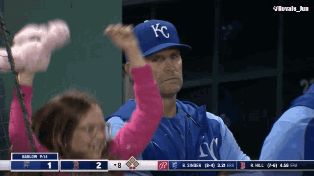 a man wearing a blue kc hat holds a little girl in his arms