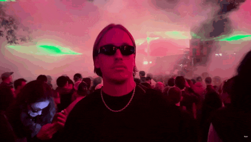 a man wearing sunglasses is standing in a crowd of people