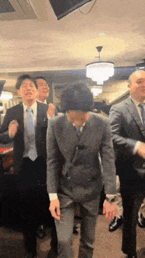 a group of men in suits are dancing together