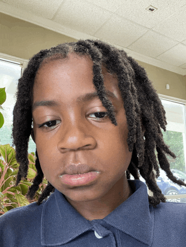 a young boy with dreadlocks wearing a blue shirt