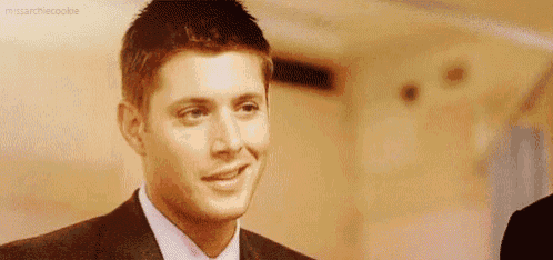 a man in a suit and tie is smiling for the camera .