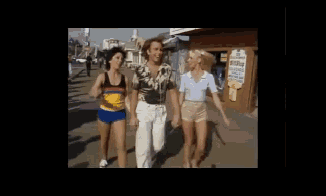 a man and two women are walking down a street with the words three 's company on the bottom