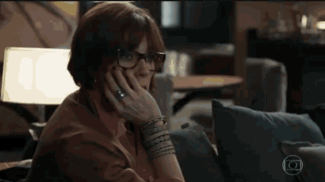 a woman wearing glasses is sitting on a couch