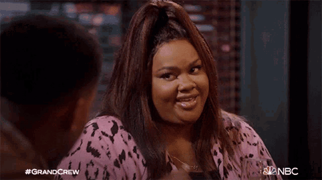 a woman in a pink leopard print shirt is talking to a man ..