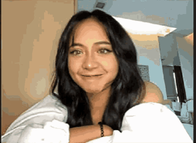 a woman with long black hair is smiling for the camera