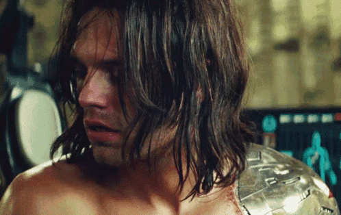 a close up of a man with long hair and a metal armor