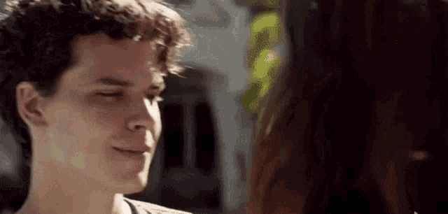 a young man and a young woman are looking at each other and smiling .