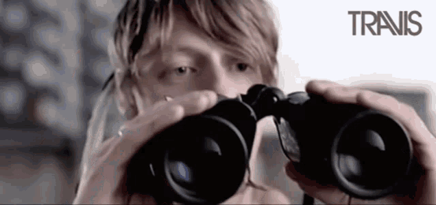 a man looking through binoculars with the word travis on the bottom right