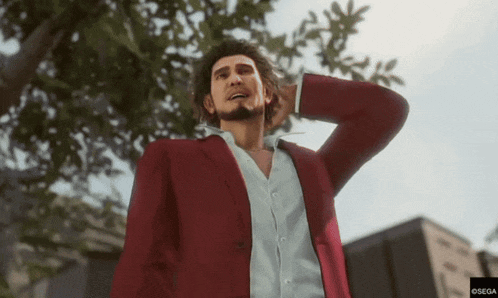 a man in a red suit and white shirt is standing in front of a tree