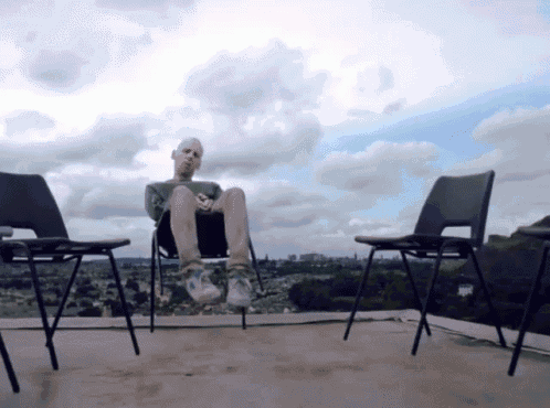 a man sits on a chair with his feet up in front of a cloudy sky