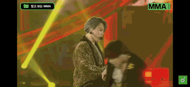 a man in a zebra print jacket is standing on a stage with a microphone .