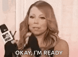 mariah carey is holding a microphone and saying okay , i 'm ready .