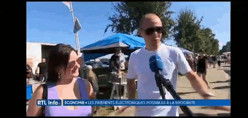 a man is talking into a microphone while a woman looks on while rtl info is displayed on the screen