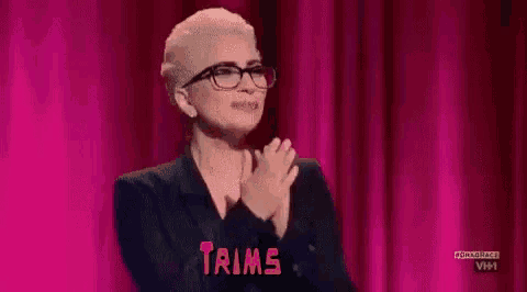 lady gaga is clapping her hands on a stage while wearing glasses .