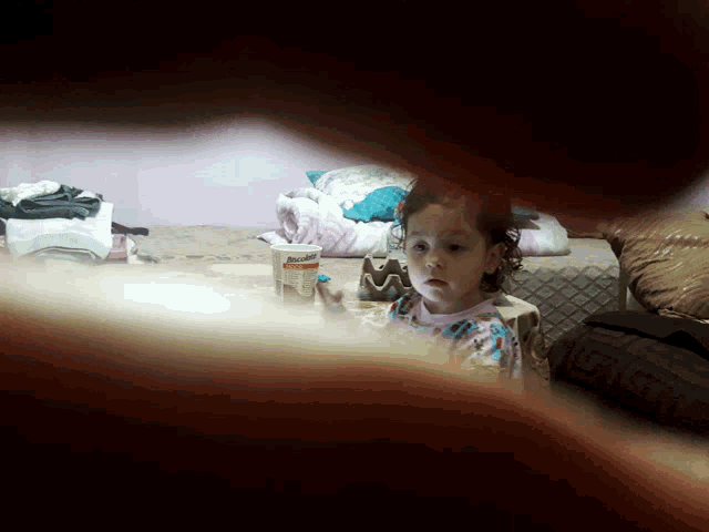a little girl looking at herself in a mirror with a bottle of toothpaste in the background