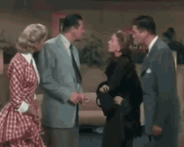 a group of people are standing next to each other in a living room and talking to each other .