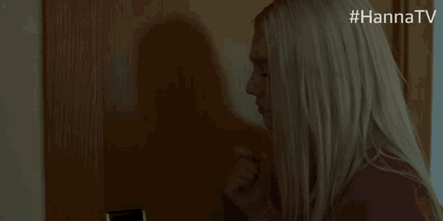 a woman in a pink shirt is standing in front of a door with #hannatv written above her