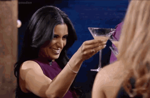a woman in a purple dress is toasting with a martini glass