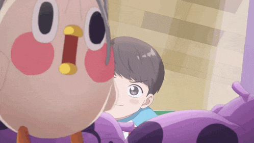 a boy is looking at a stuffed animal with a cartoon face